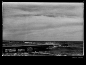 Bathing jetty by Micha Holland. The black-and-white photo shows a bathing jetty leading into rough autumn sea.